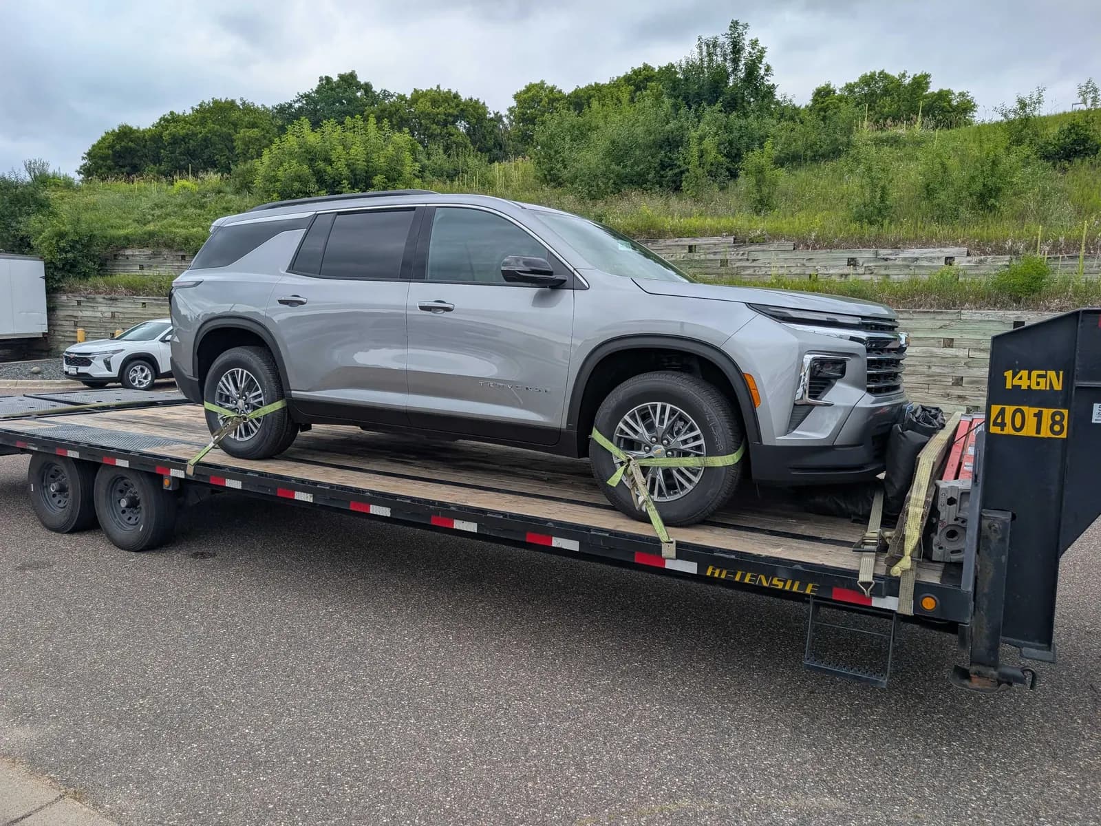 New SUV strapped to a gooseneck flatbed trailer for expedited transport